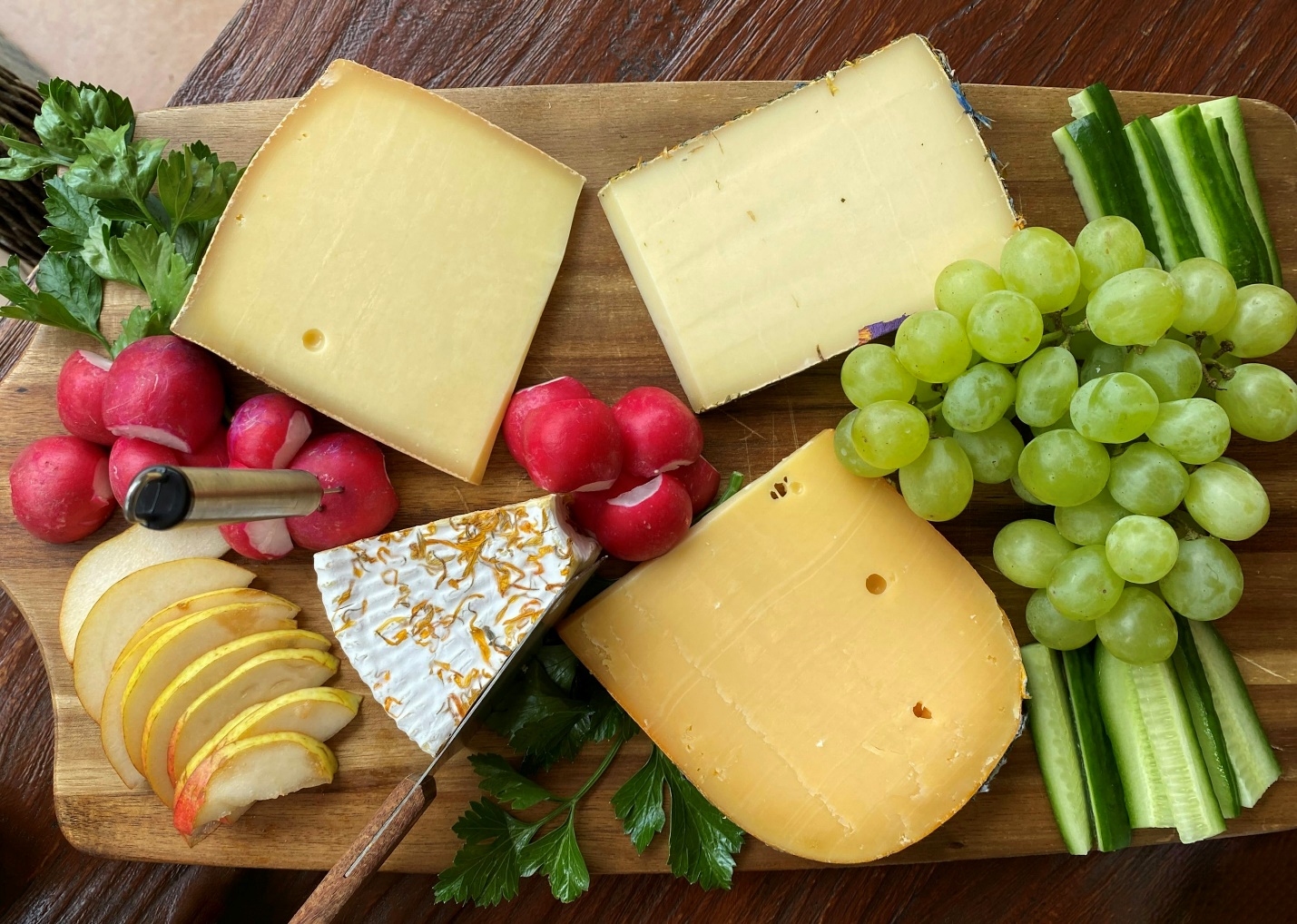 a wooden cutting board topped with cheese and fruit