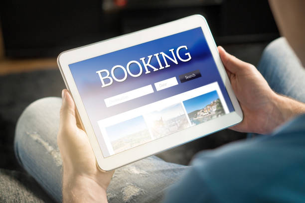 Booking app or website on tablet screen. Man searching hotel and flights for holiday and vacation with travel application. Booking app or website on tablet screen. Man searching hotel and flights for holiday and vacation with travel application. Person holding smart device in hand. How to find cheap flights stock pictures, royalty-free photos & images
