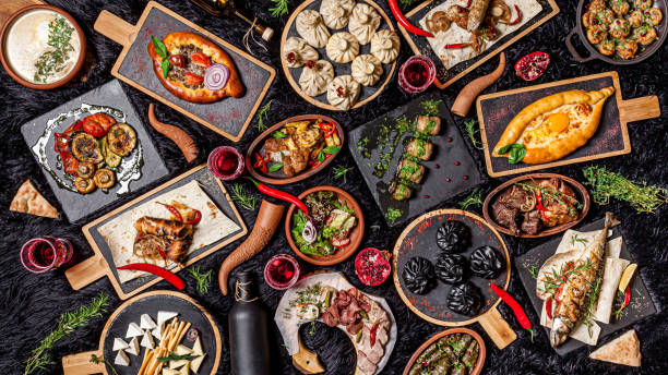 Georgian cuisine. A large laid table of different dishes for the whole family on a day off. Kebab, Lula, Lavash, Suluguni cheese, Khachipuri, Khinkali. background image, top view Georgian cuisine. A large laid table of different dishes for the whole family on a day off. Kebab, Lula, Lavash, Suluguni cheese, Khachipuri, Khinkali. background image, top view What to Eat When Traveling to New Cultures stock pictures, royalty-free photos & images