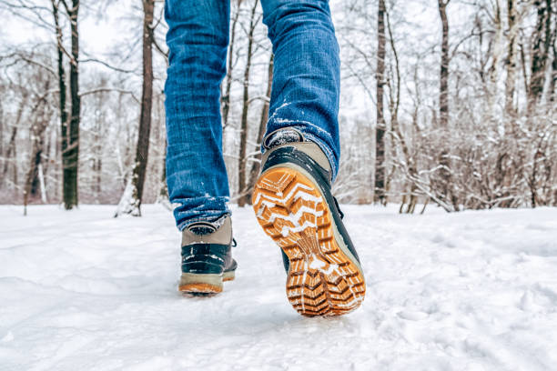 Man's legs in black with orange boots walking in the snow Man's legs in black with orange boots walking in the snow Comfortable shoes for travel stock pictures, royalty-free photos & images