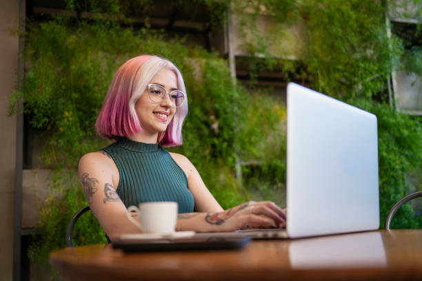 Woman with tattoo and pink hair working at cafe Woman with tattoo and pink hair working at cafe Co-working and coffee culture stock pictures, royalty-free photos & images